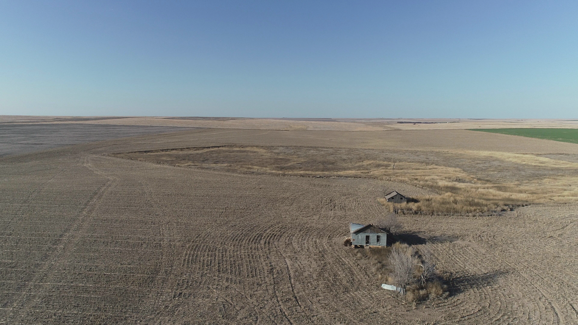 An aerial view of a desert landscape with a house in the middle of it.