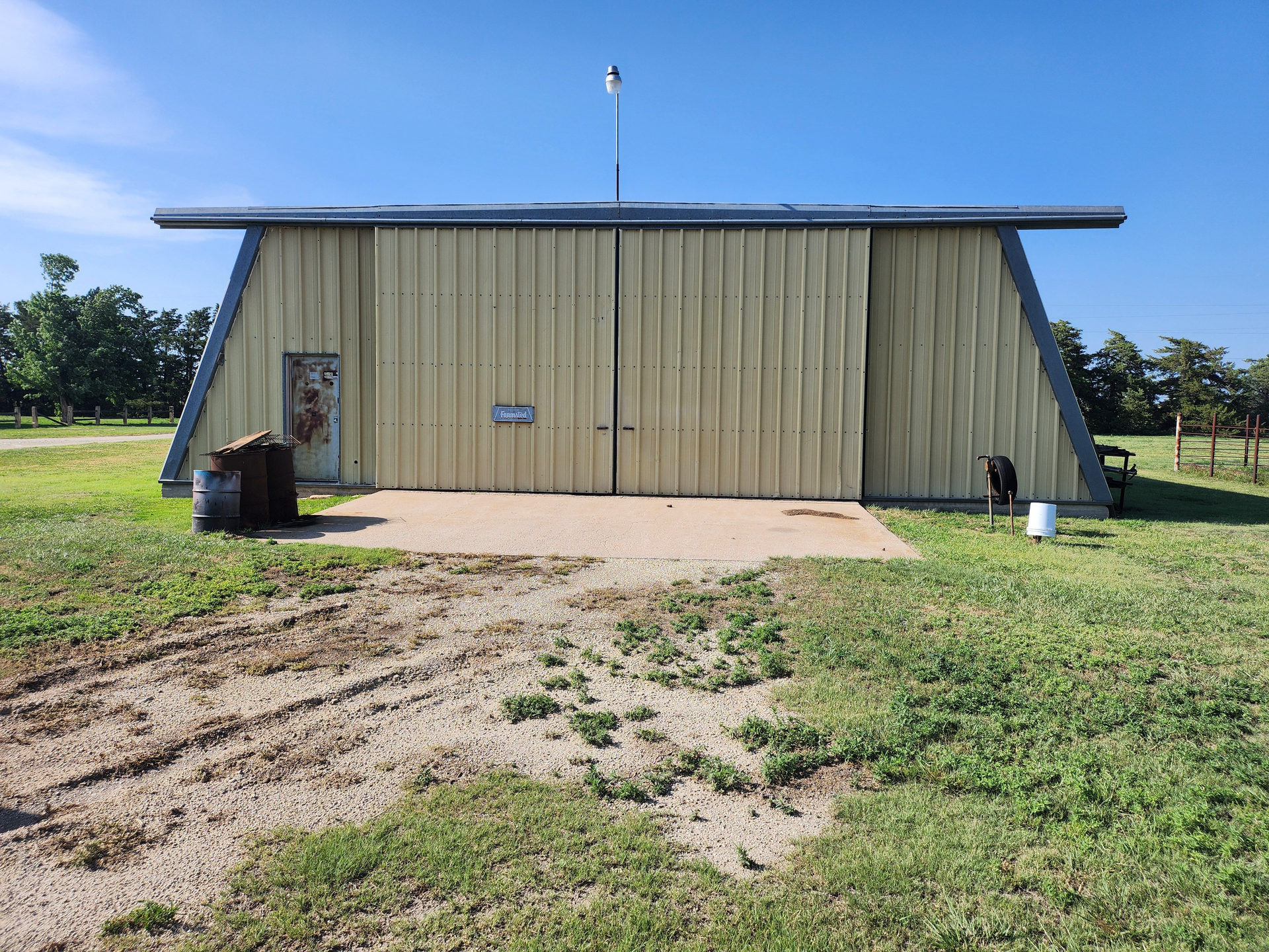 A large metal building is sitting in the middle of a grassy field.