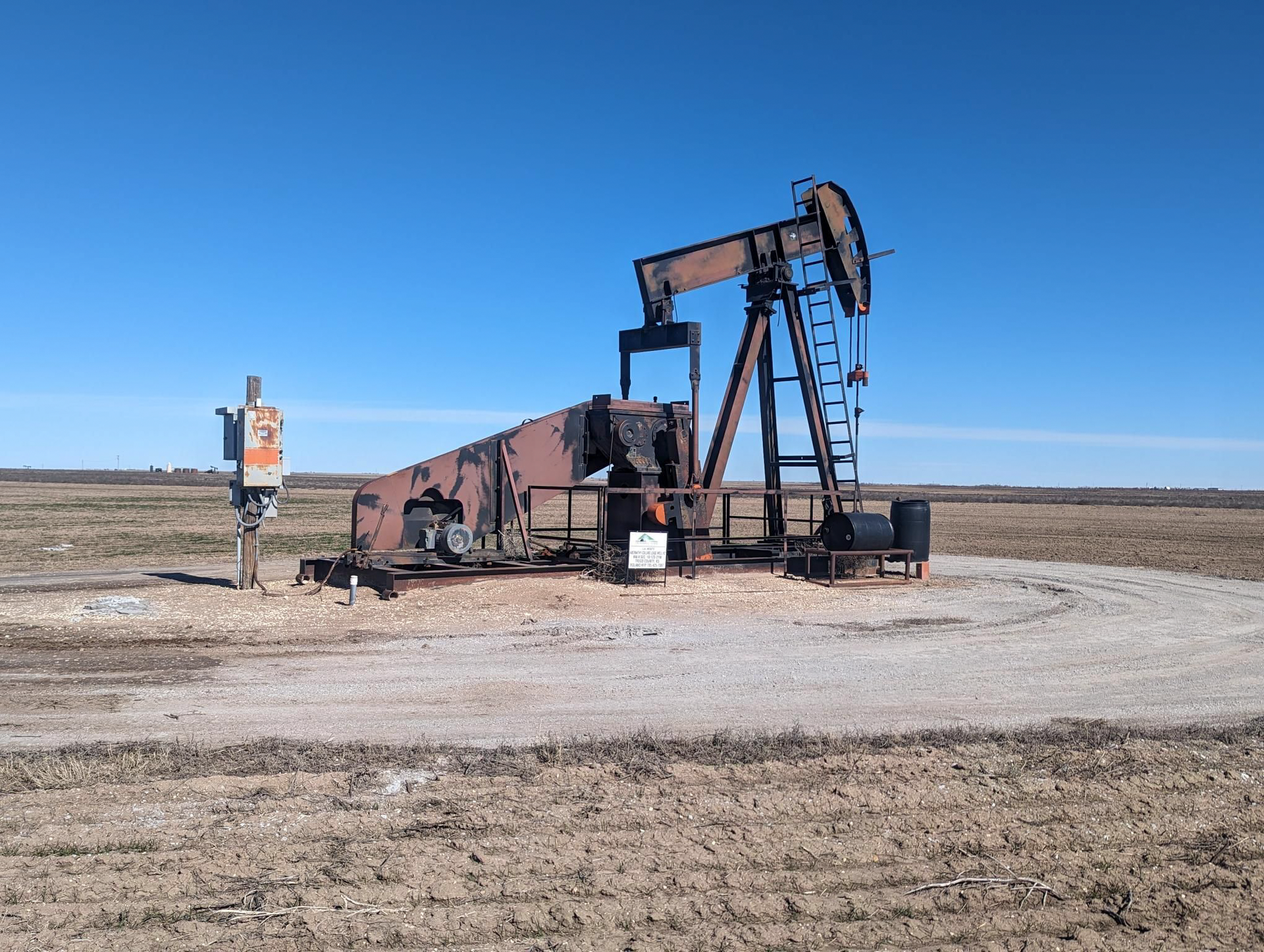 An oil pump is in the middle of a dirt field