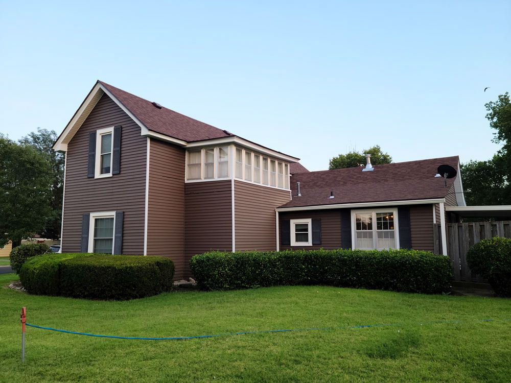 A brown house with a red roof and a hose in front of it