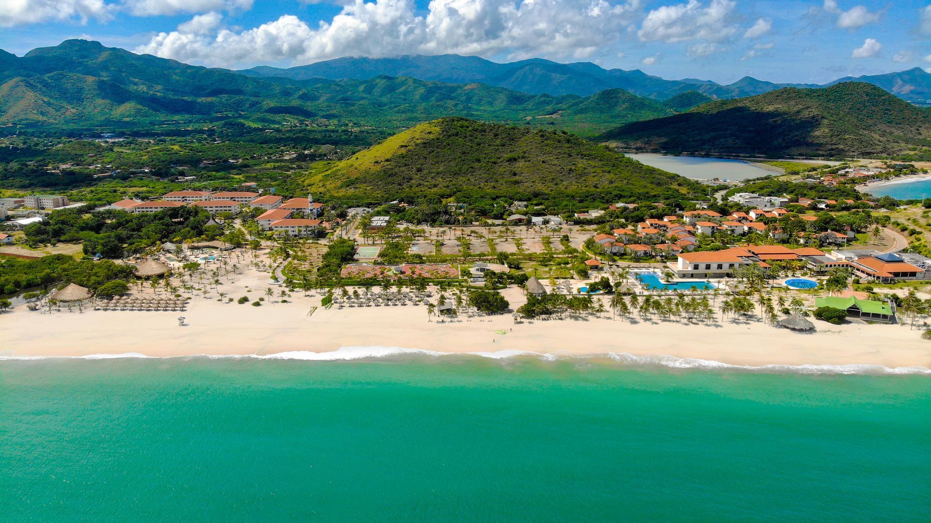 Un hombre y una mujer caminan por una playa con palmeras.