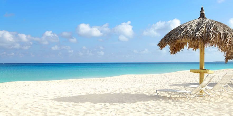 Una playa con una sombrilla de paja y sillas