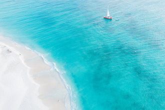 Un hombre y una mujer caminan por la playa tomados de la mano.