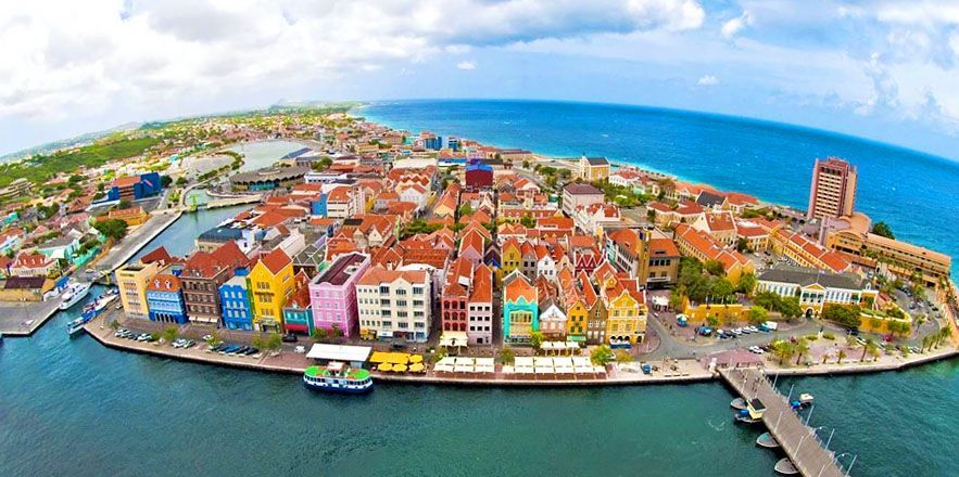 Un hombre y una mujer caminan por la playa tomados de la mano.
