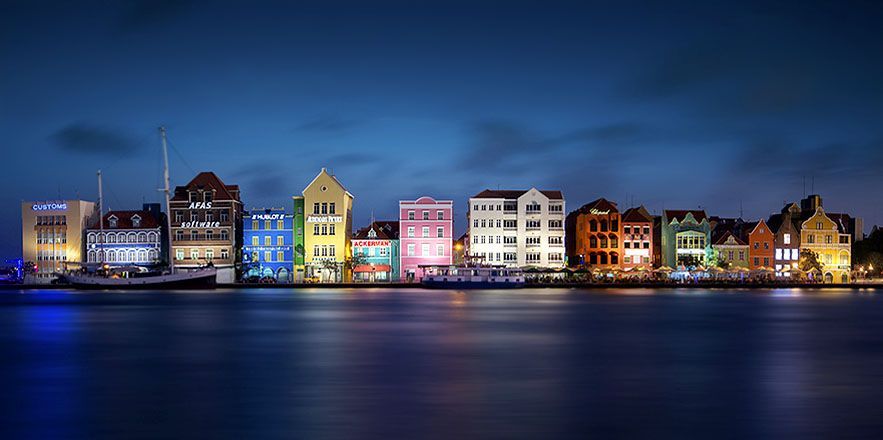 Una hilera de edificios coloridos junto a un cuerpo de agua por la noche.
