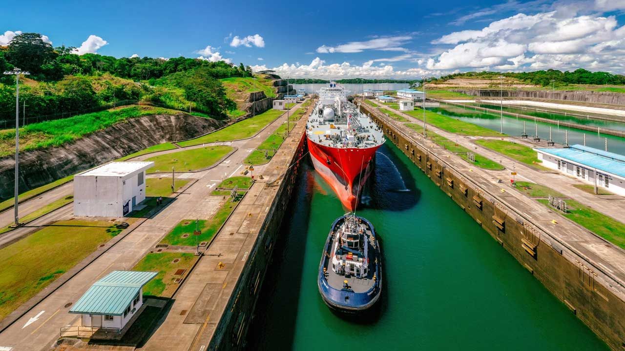 Un gran barco está siendo remolcado a través de un canal por un remolcador.