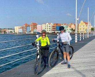 Un hombre y una mujer caminan por la playa tomados de la mano.