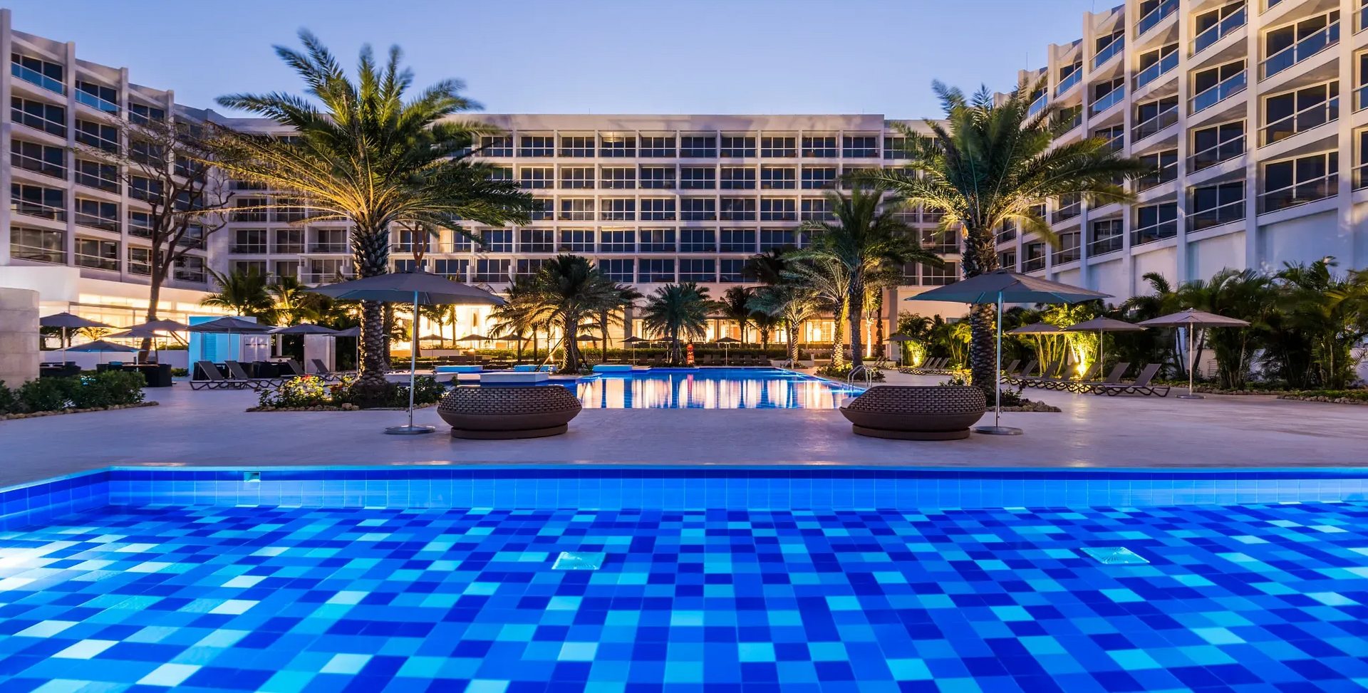 Una calle estrecha bordeada de edificios y balcones con una torre de reloj al fondo.