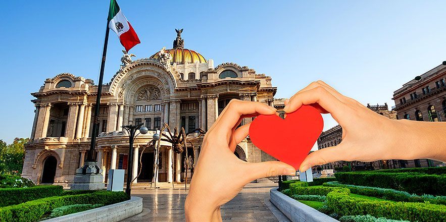 Una persona está formando un corazón con las manos frente a un edificio.
