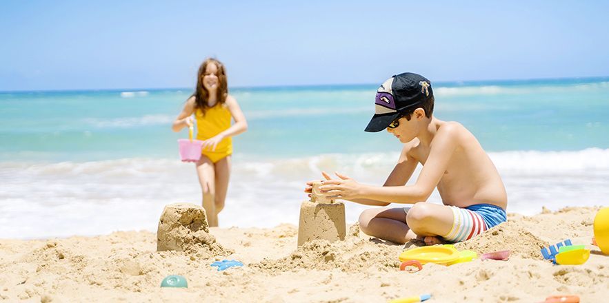Un niño y una niña juegan en la arena de la playa.