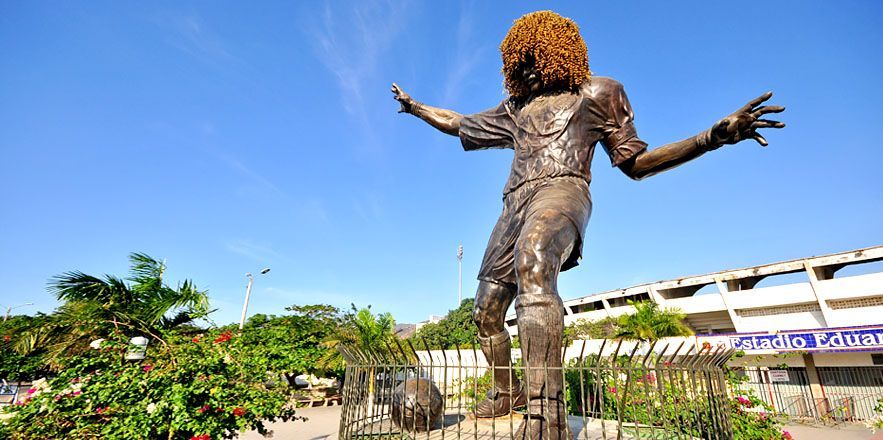 Una estatua de un hombre con un gran afro está parada frente a un edificio.