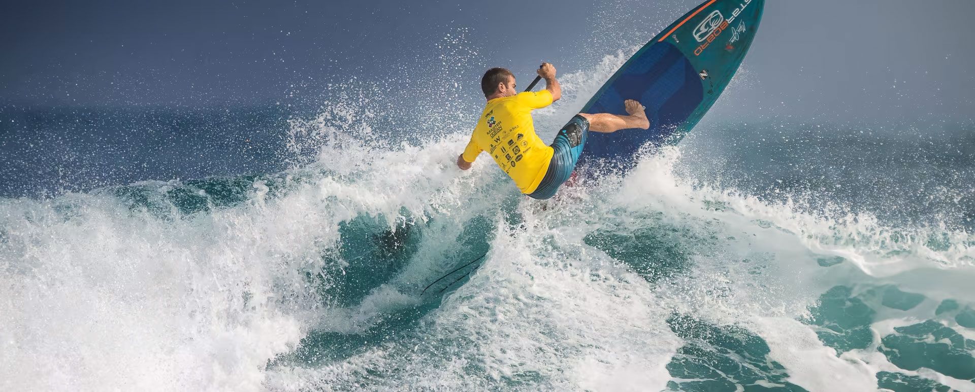 Un hombre está surfeando sobre una ola en una tabla de surf en el océano.