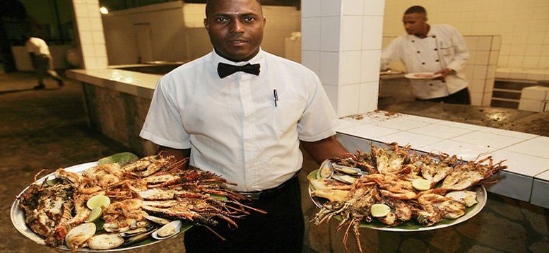 Un hombre con pajarita sostiene dos bandejas de comida.