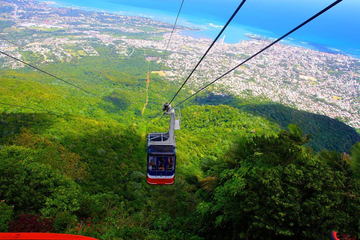 Un teleférico sube a una montaña con vistas a una ciudad.