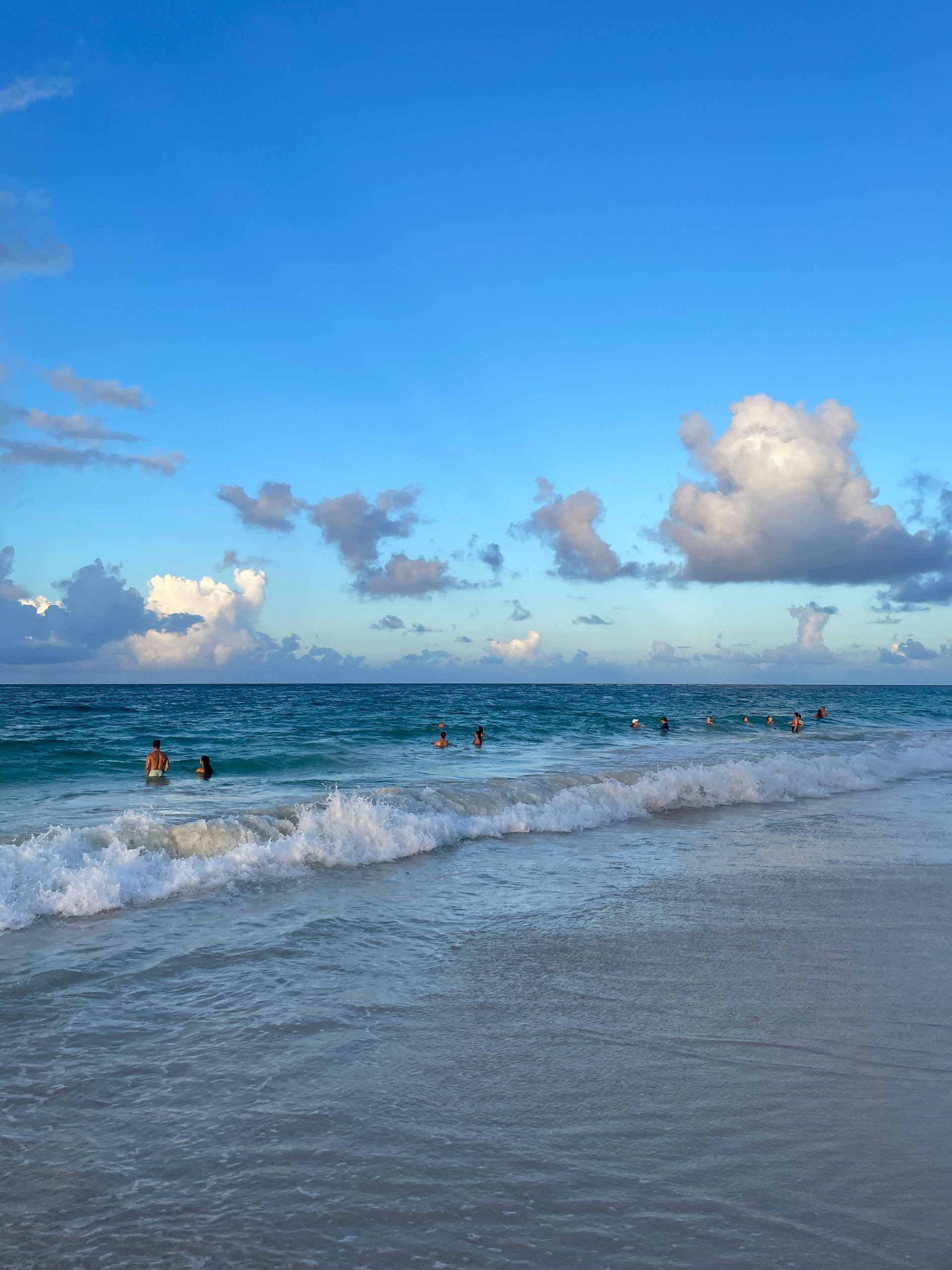 Un hombre y una mujer caminan por una playa con palmeras.