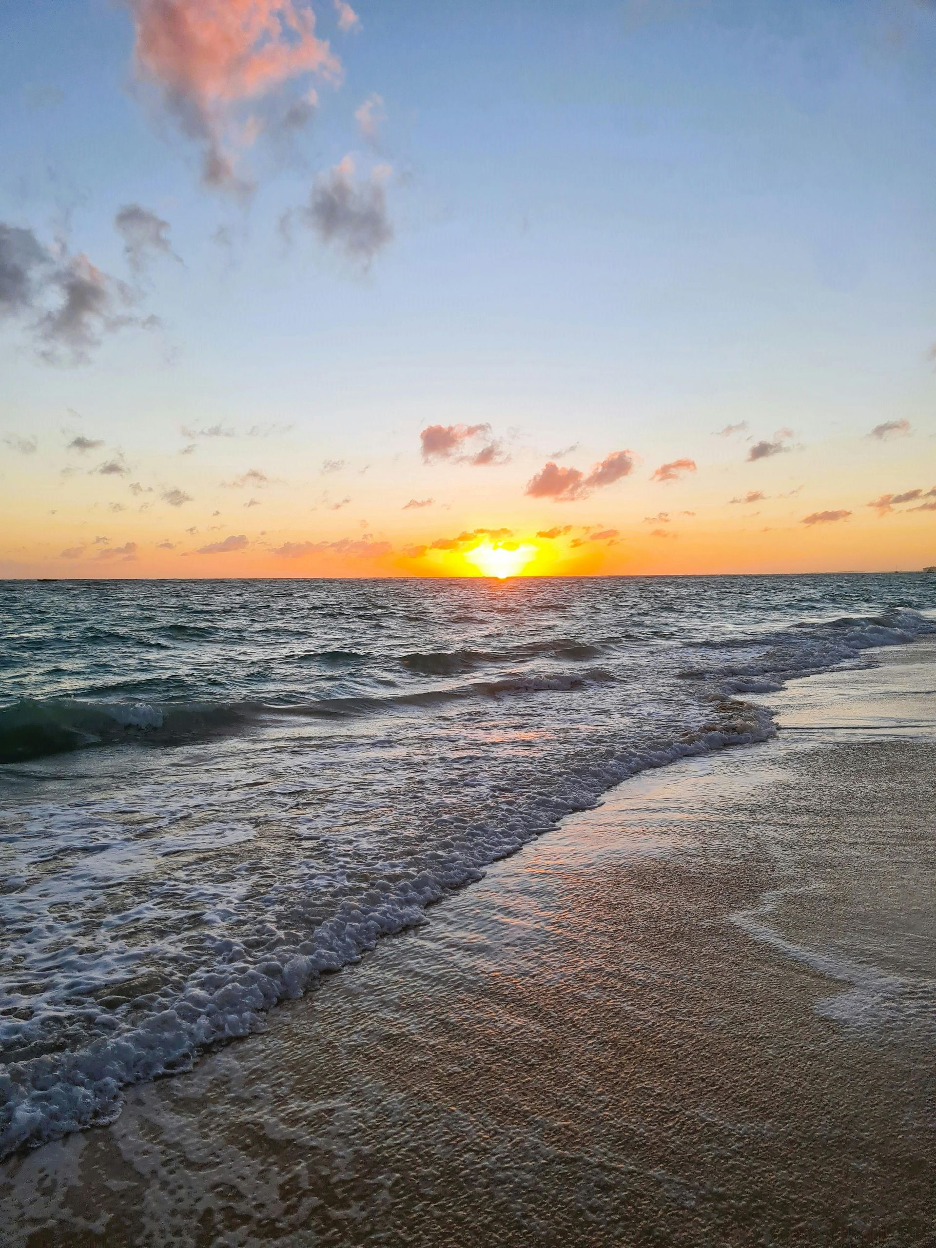 El sol se pone sobre el océano en una playa.