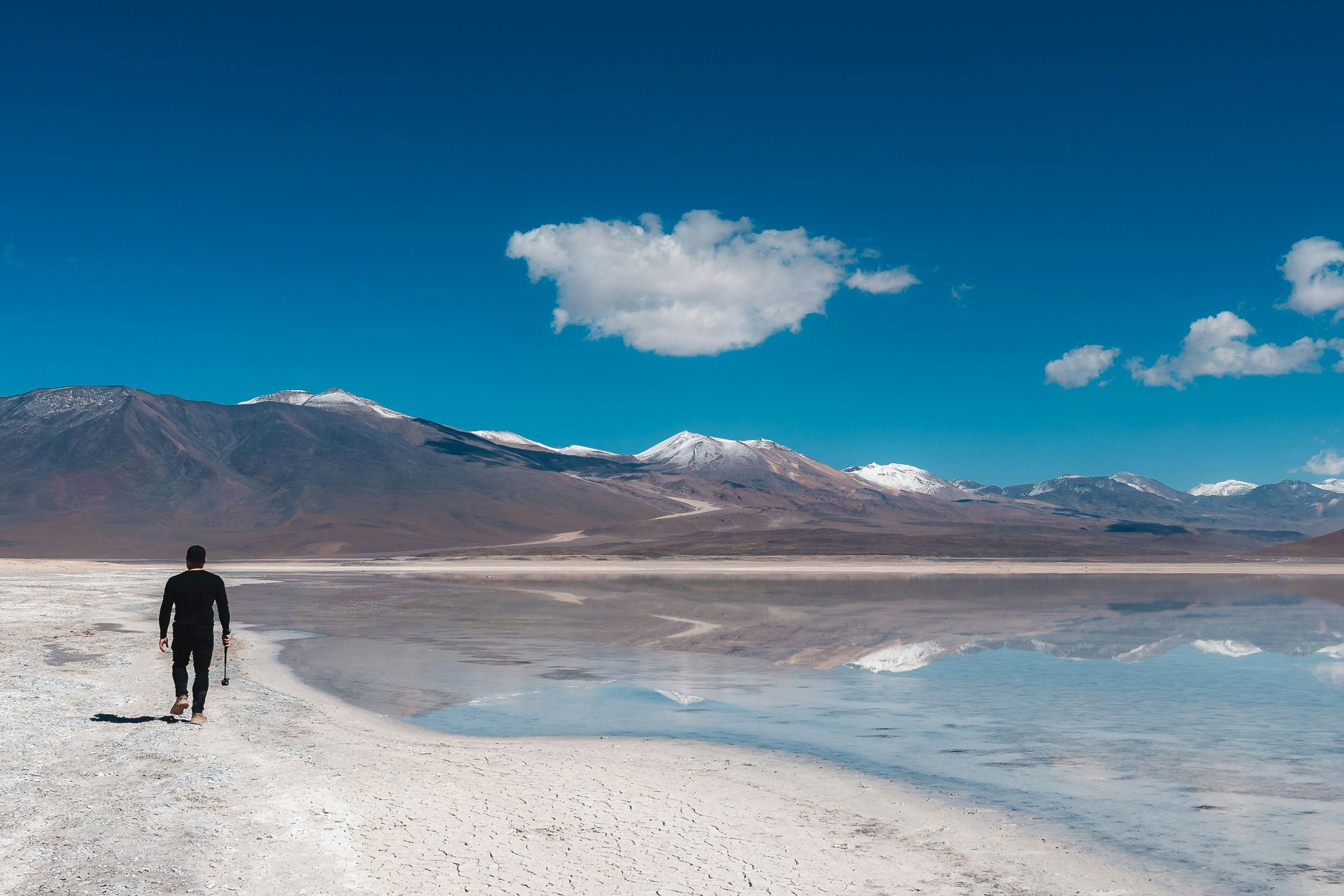 Un hombre y una mujer caminan por una playa con palmeras.