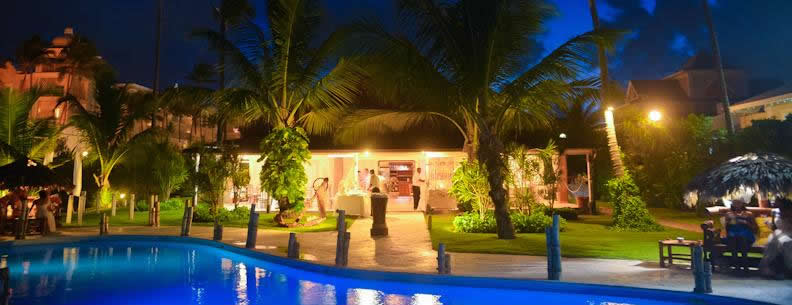 Por la noche, una gran piscina está rodeada de palmeras.