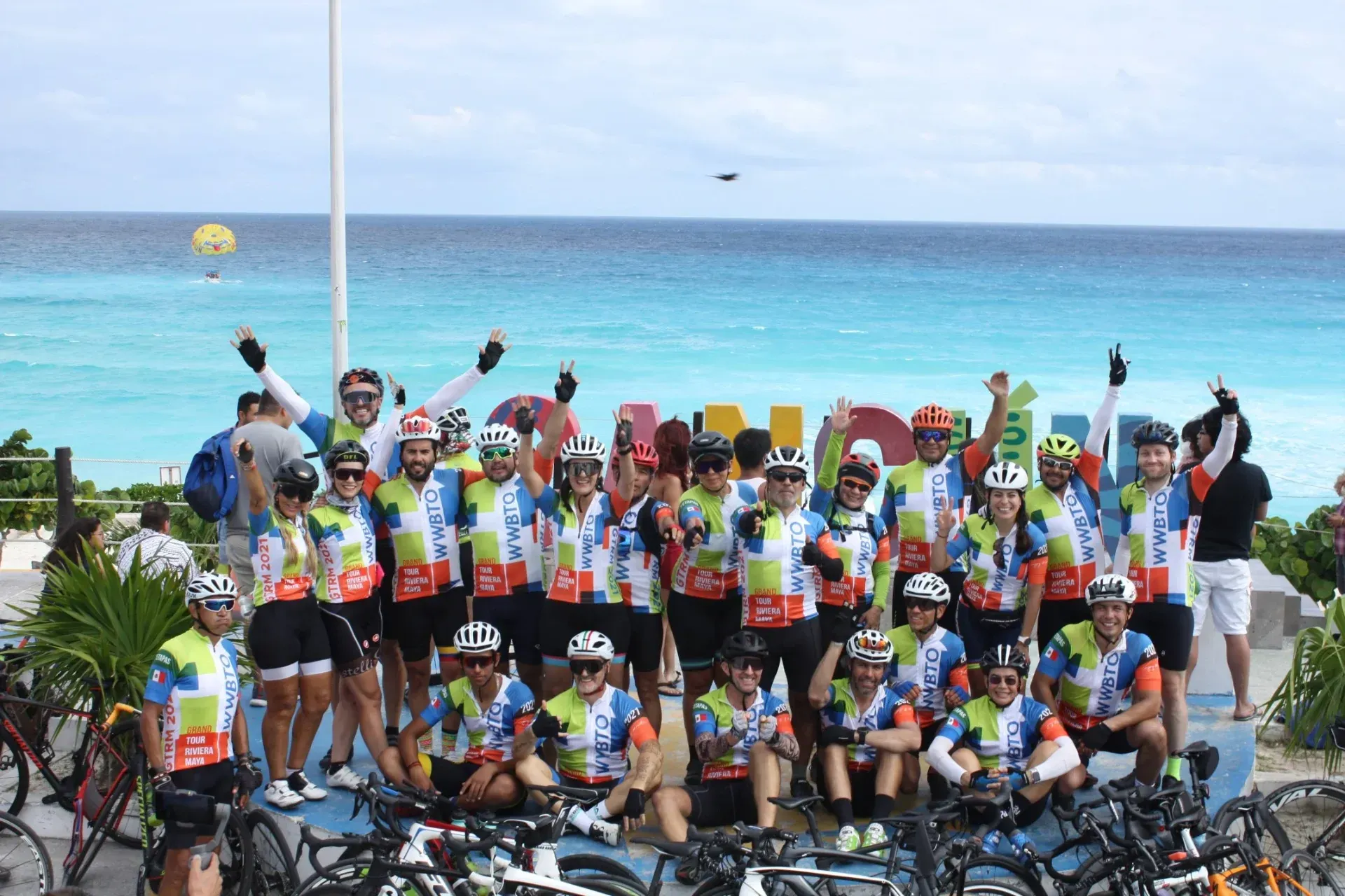 Un grupo de ciclistas posan para una fotografía frente al océano.
