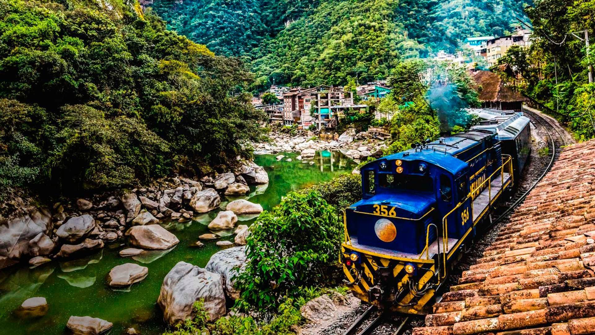 Un tren azul pasa por las vías al lado de un río.