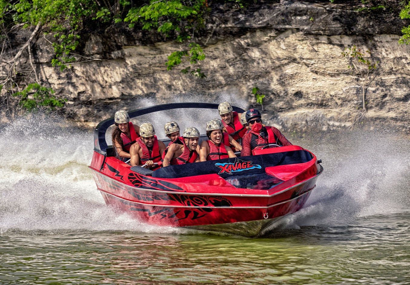 Un grupo de personas viaja en una lancha rápida roja en un río.