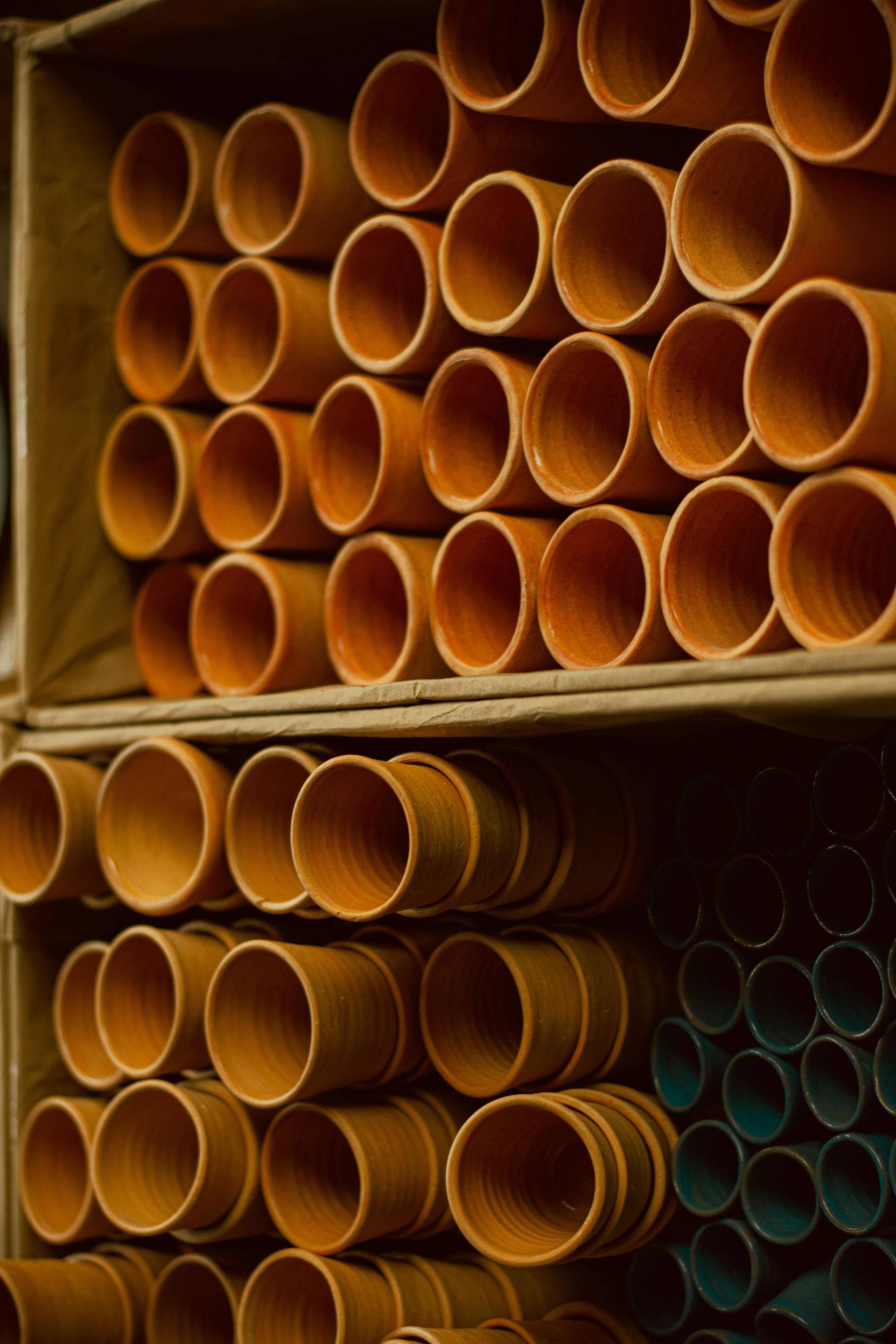 Shelves stacked with orange PVC pipes and some blue ones in a warehouse.