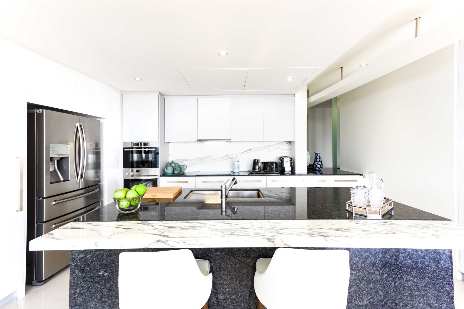 Modern white kitchen with stainless steel appliances, dark island, and granite countertops. Modern white kitchen with stainless steel appliances, dark island, and granite countertops.
