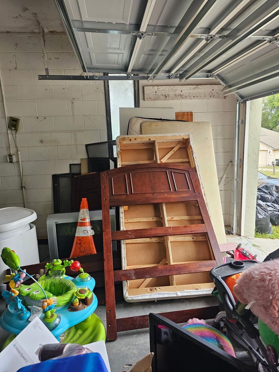 Cluttered garage with various furniture, a TV, and child's toys.