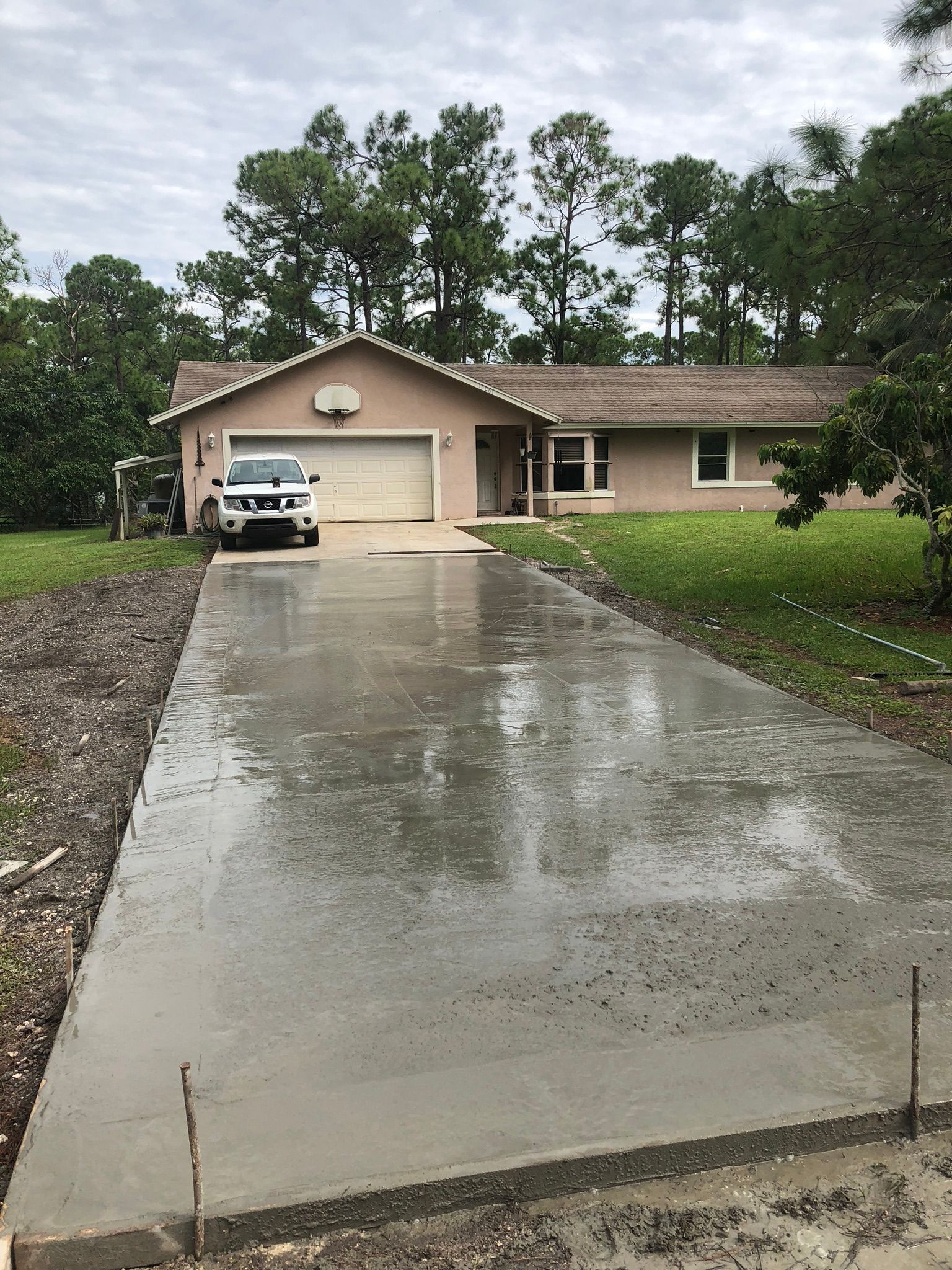 A car is parked in a concrete driveway in front of a house.