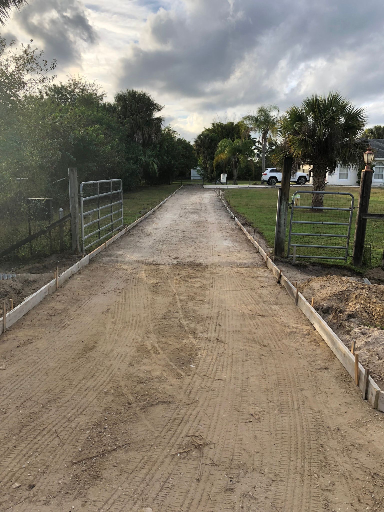A dirt road leading to a house with a gate in the middle of it.
