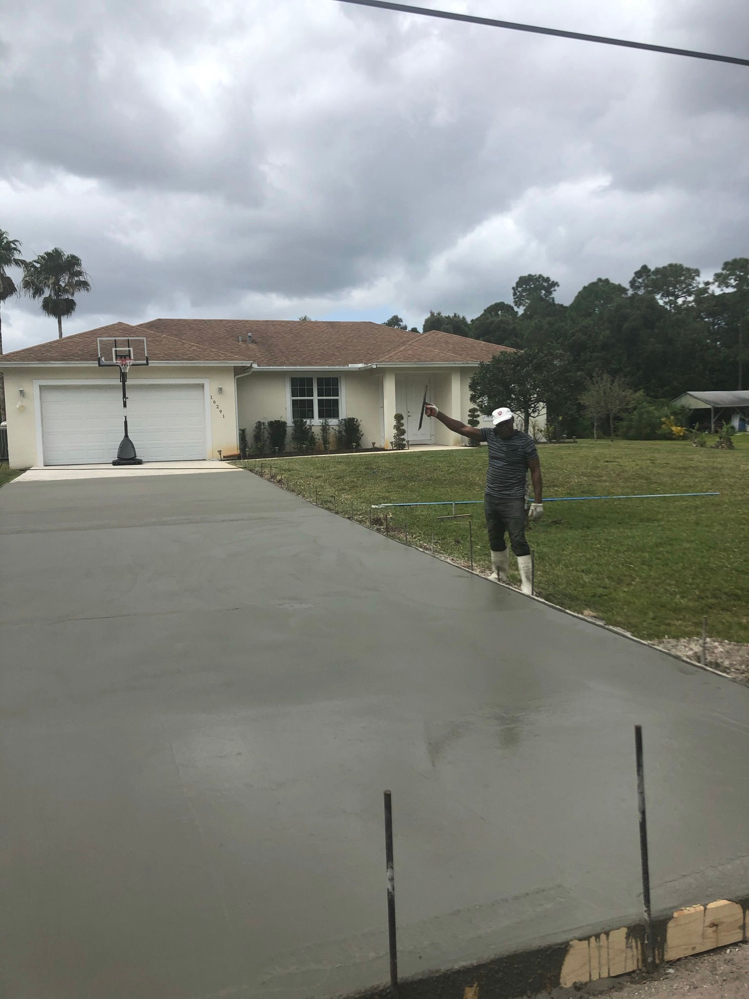 A white concrete walkway next to a garage with a car parked in the background.