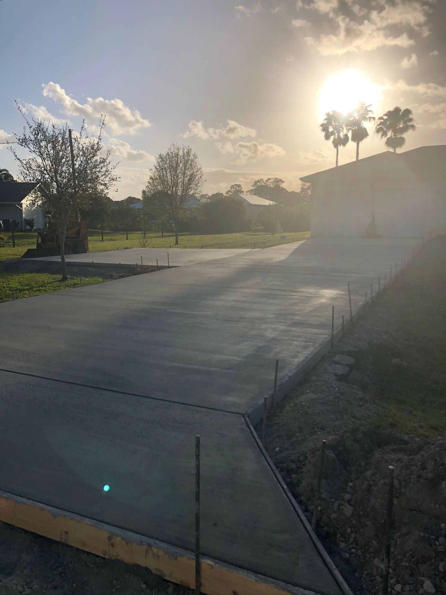 The sun is shining through the clouds over a concrete driveway.
