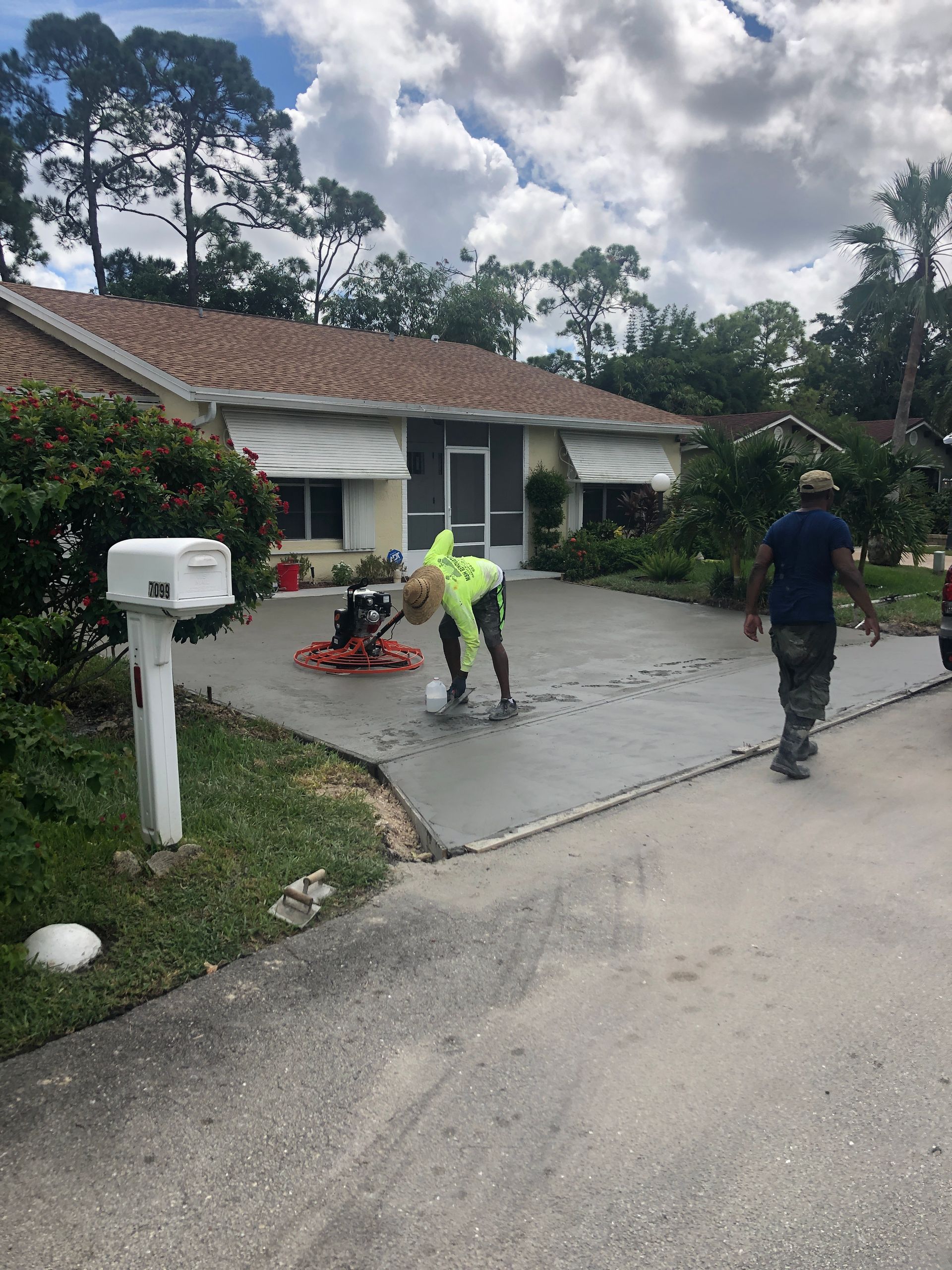 A man is working on a concrete driveway in front of a house.