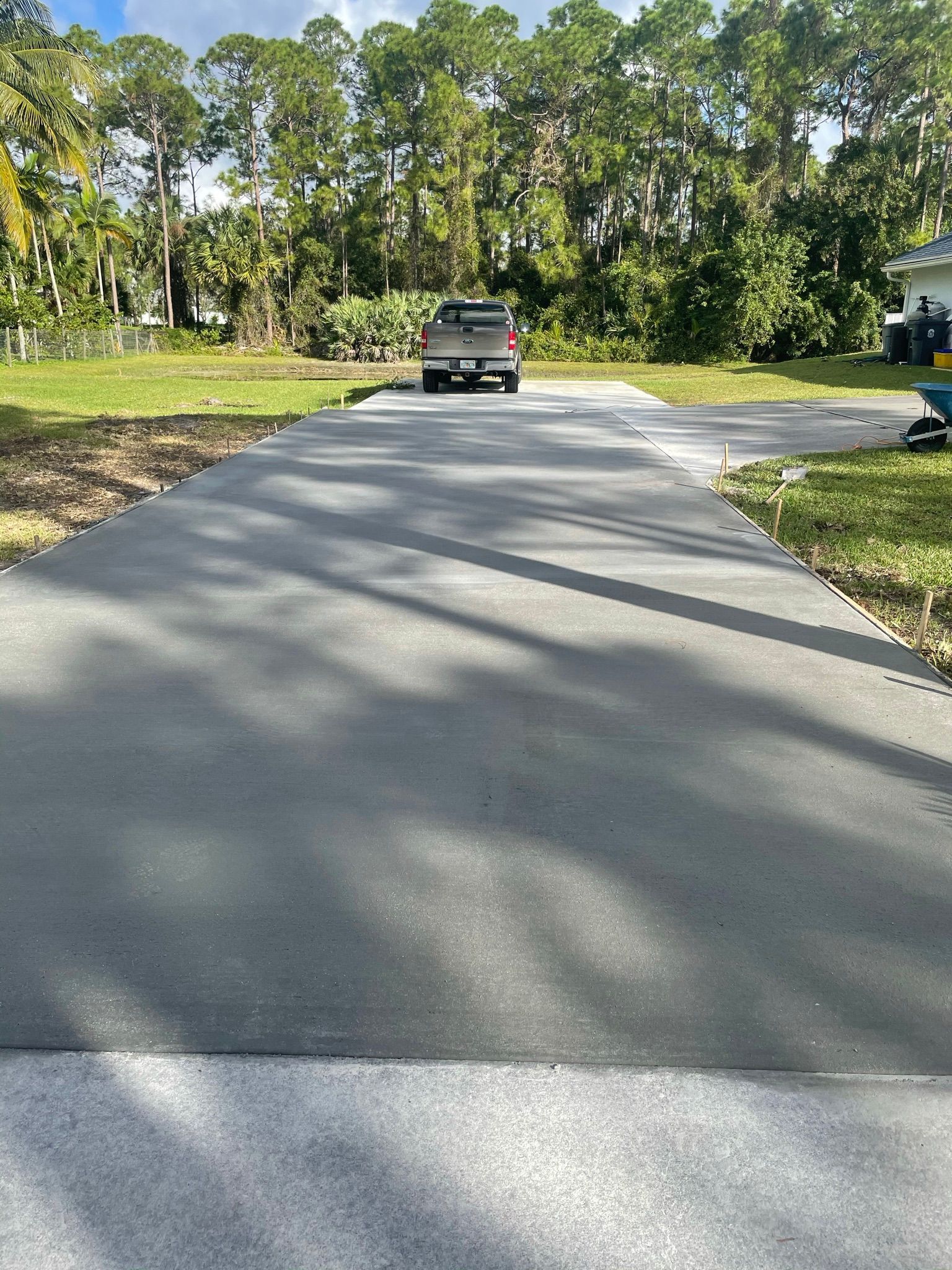 A truck is driving down a concrete driveway next to a grassy field.