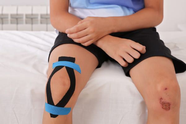 taping treatment to support a boy knee