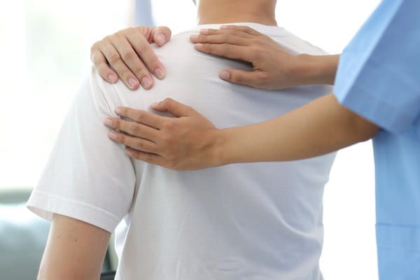 physiotherapist examining man with shoulder pain