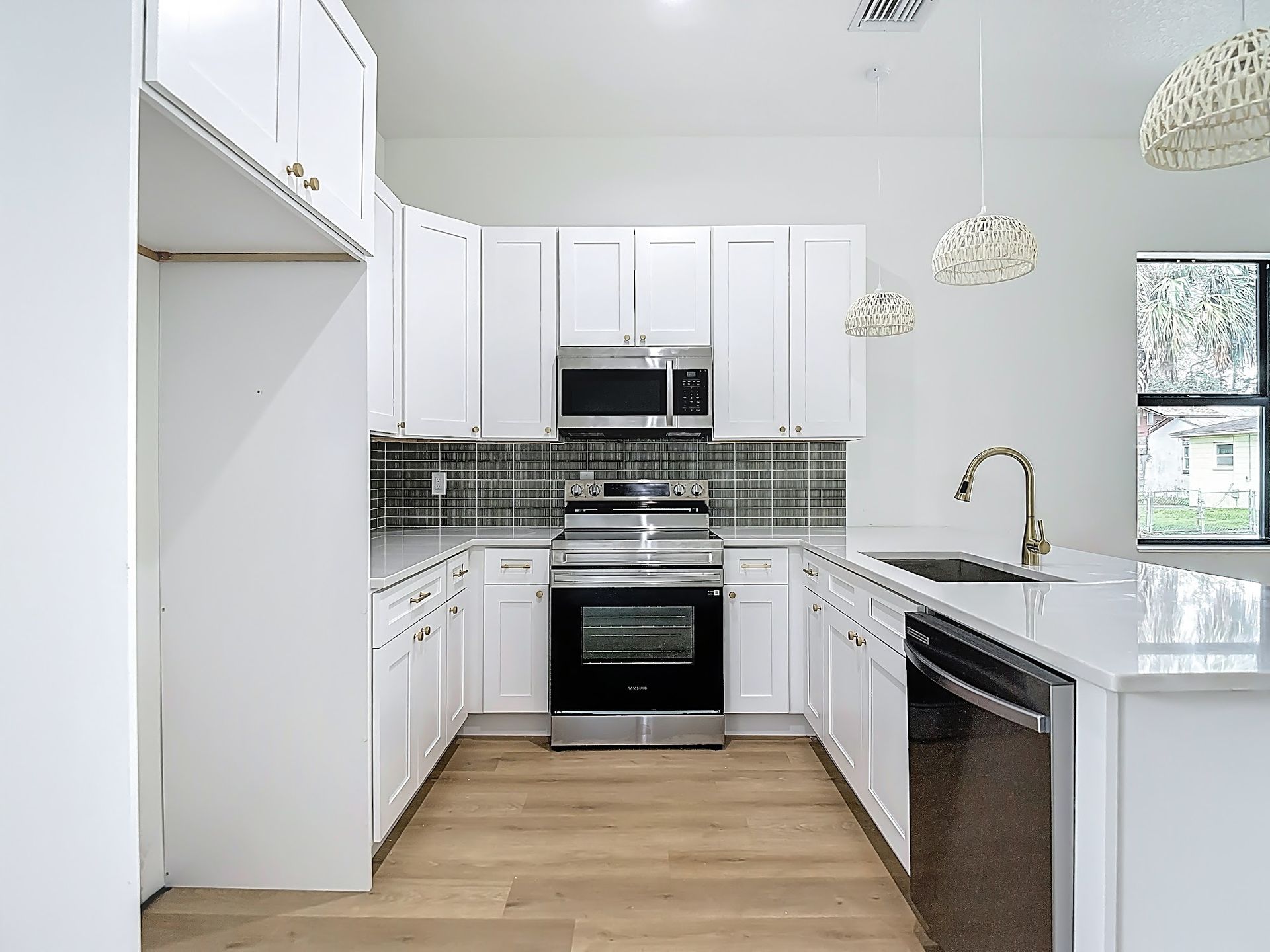 White kitchen with cabinets, stainless steel appliances, and a tiled backsplash.