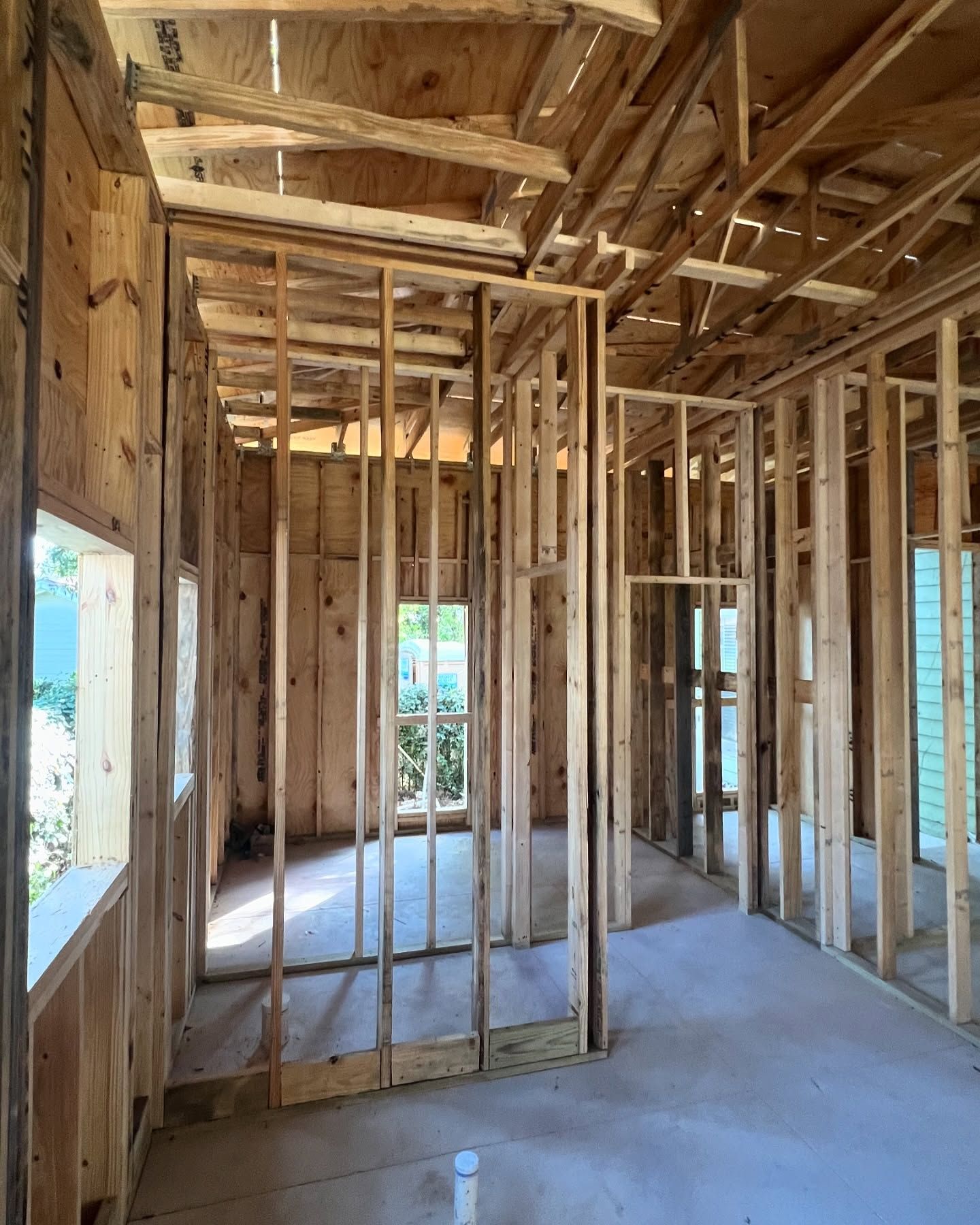 Interior view of a building under construction, showing wooden framing for walls, windows, and ceiling.