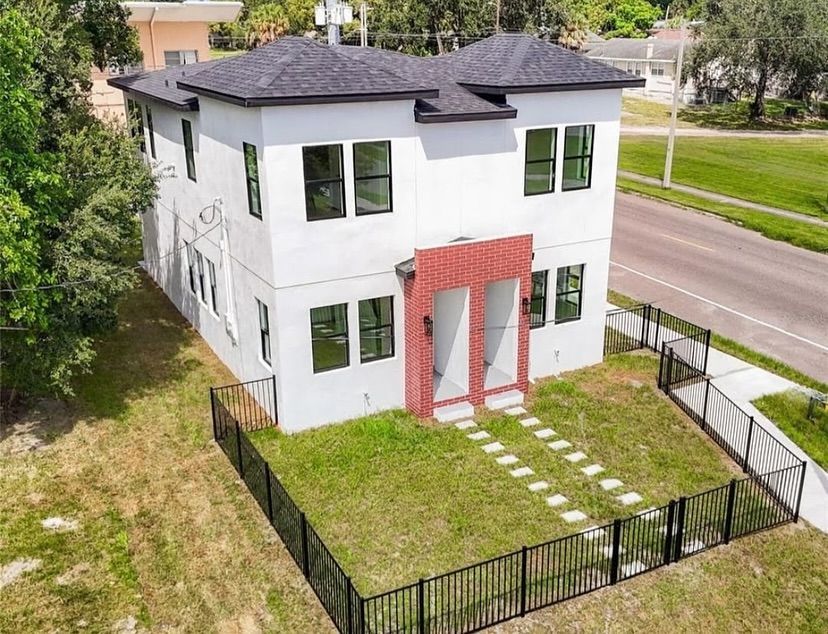 Modern white duplex with black trim, red brick accents, and black fence.