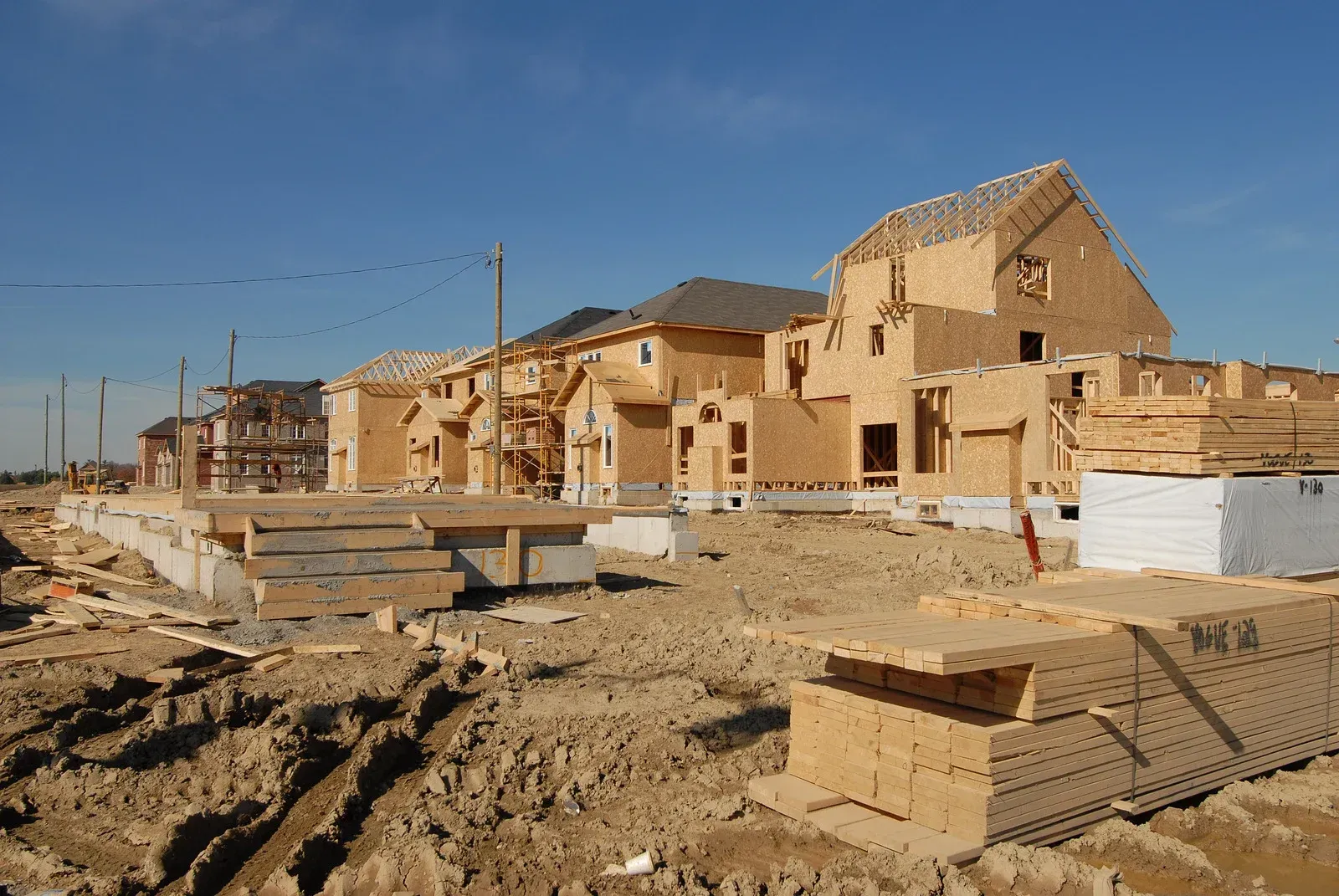 Construction site with wood-framed buildings in progress against a blue sky.