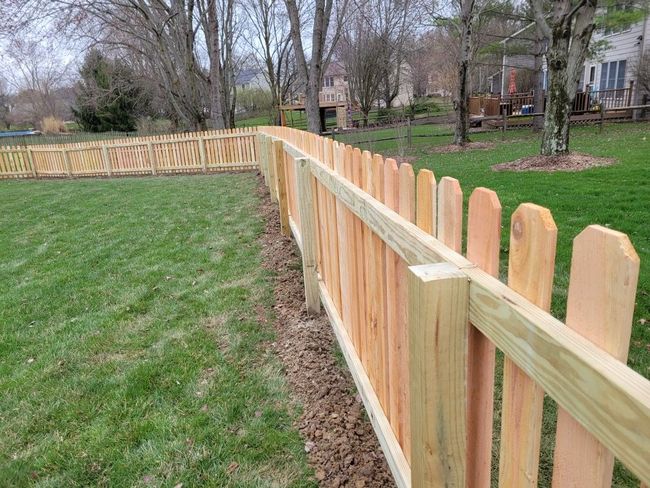 Wooden picket fence along a grassy yard in a residential neighborhood