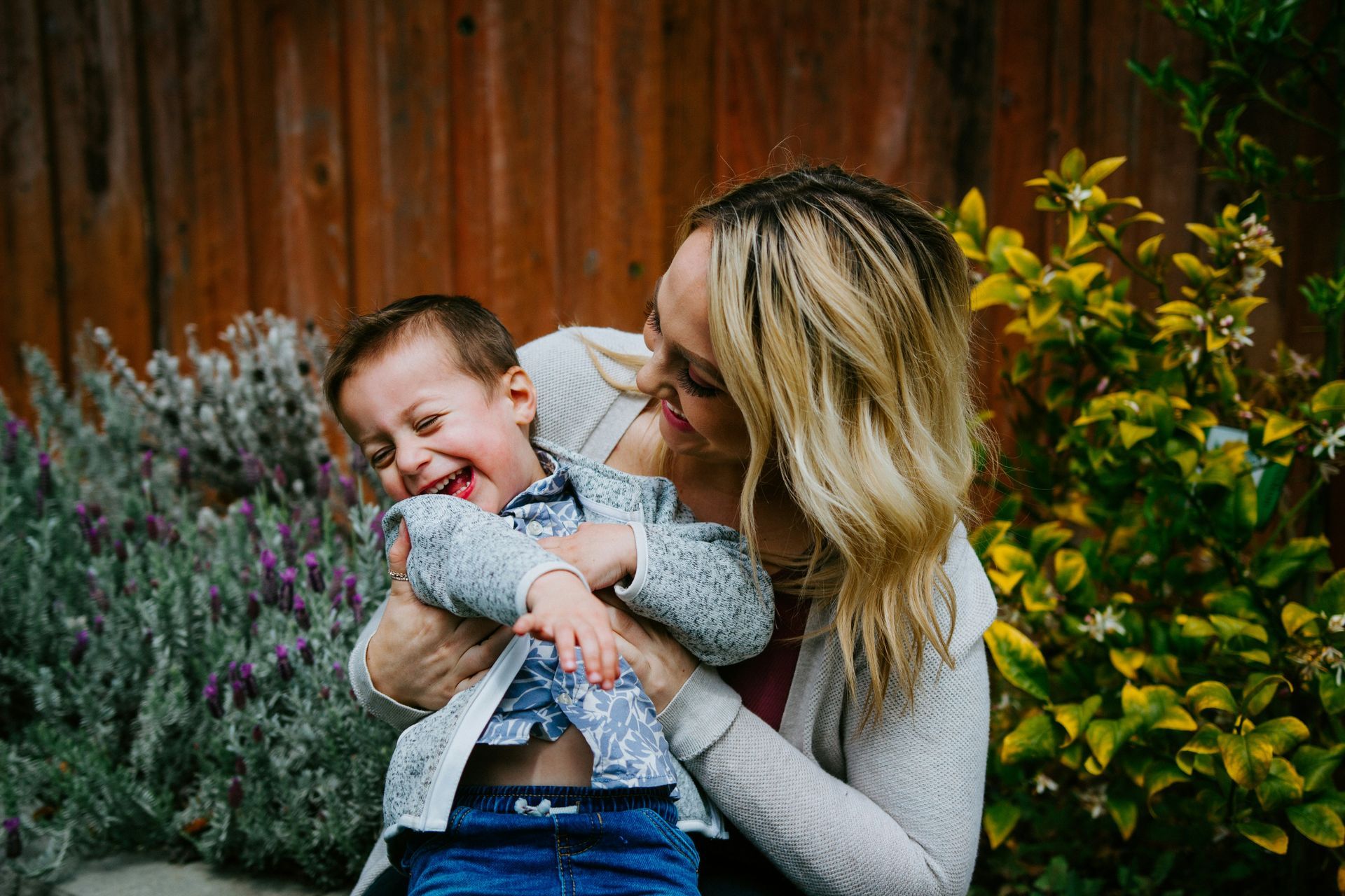 A woman is holding a baby in her arms and kissing him on the cheek.