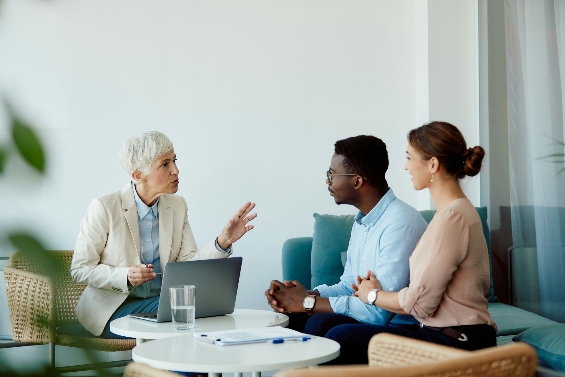 A woman is sitting at a table talking to a man and woman.