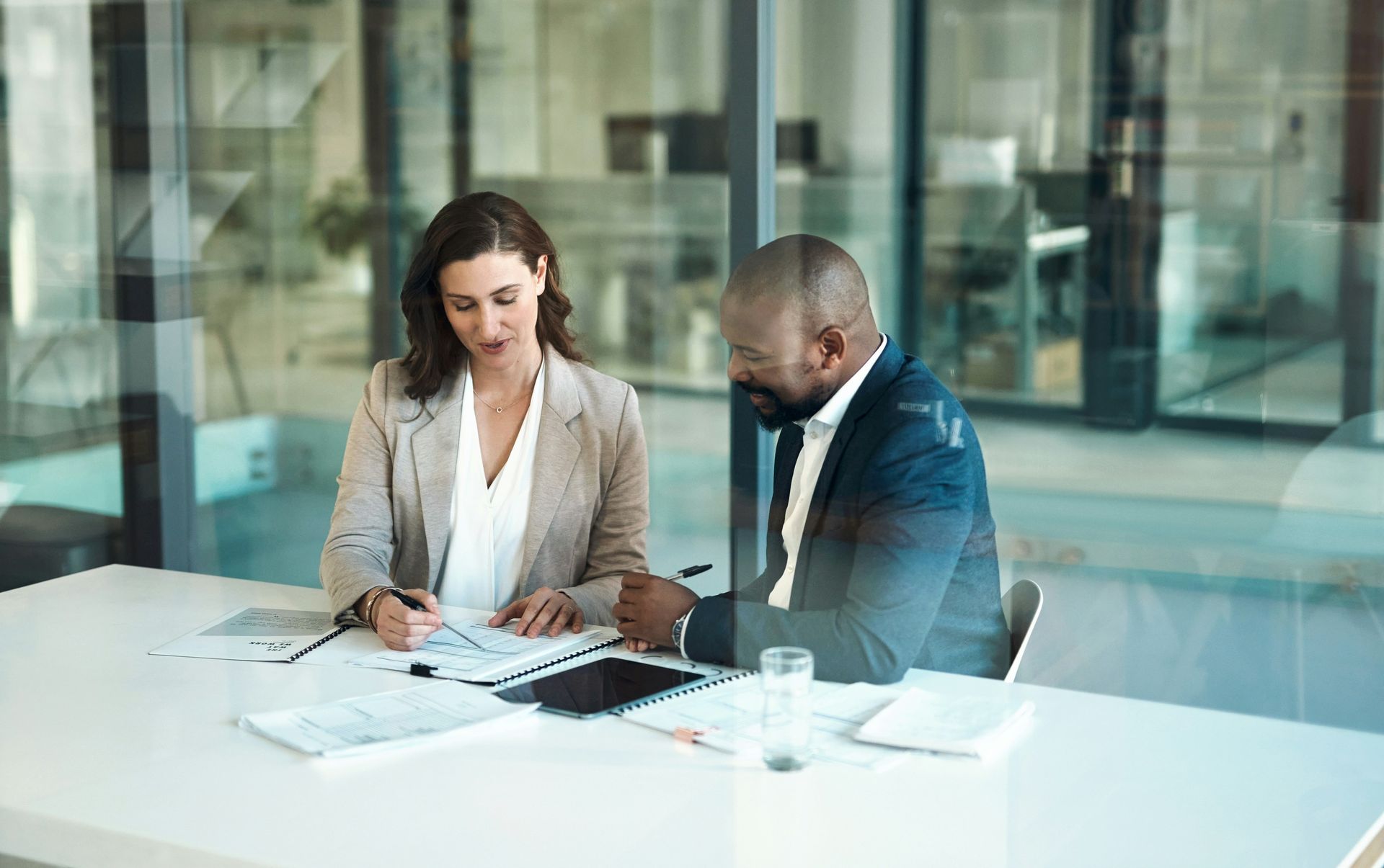 A man and a woman are sitting at a table looking at papers.