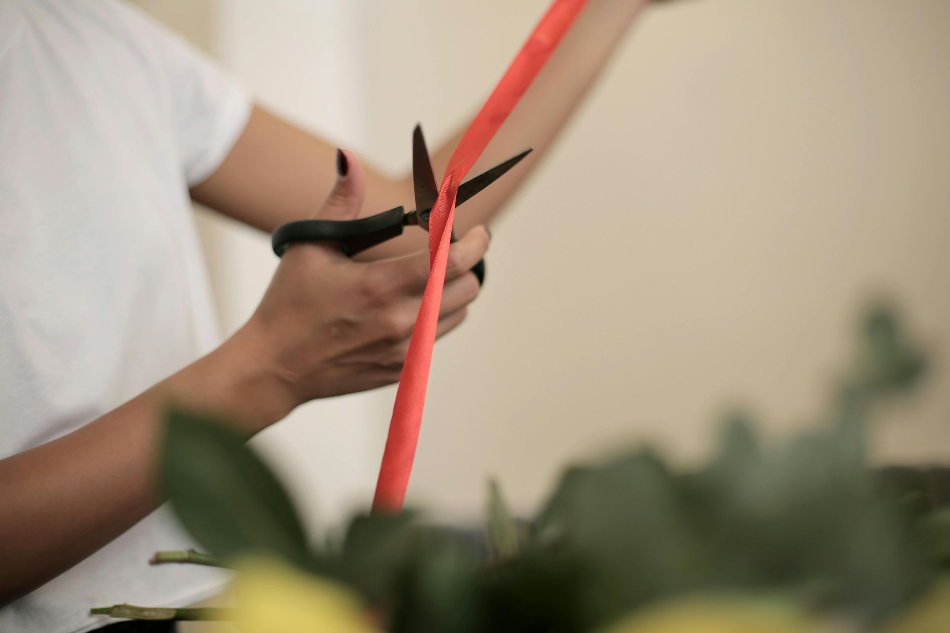 A person is cutting a red straw with scissors