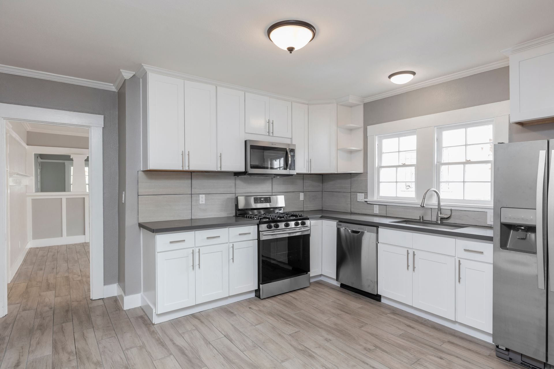 An elegant white kitchen with pristine granite countertops, a modern stove, and a sleek stainless steel refrigerator.