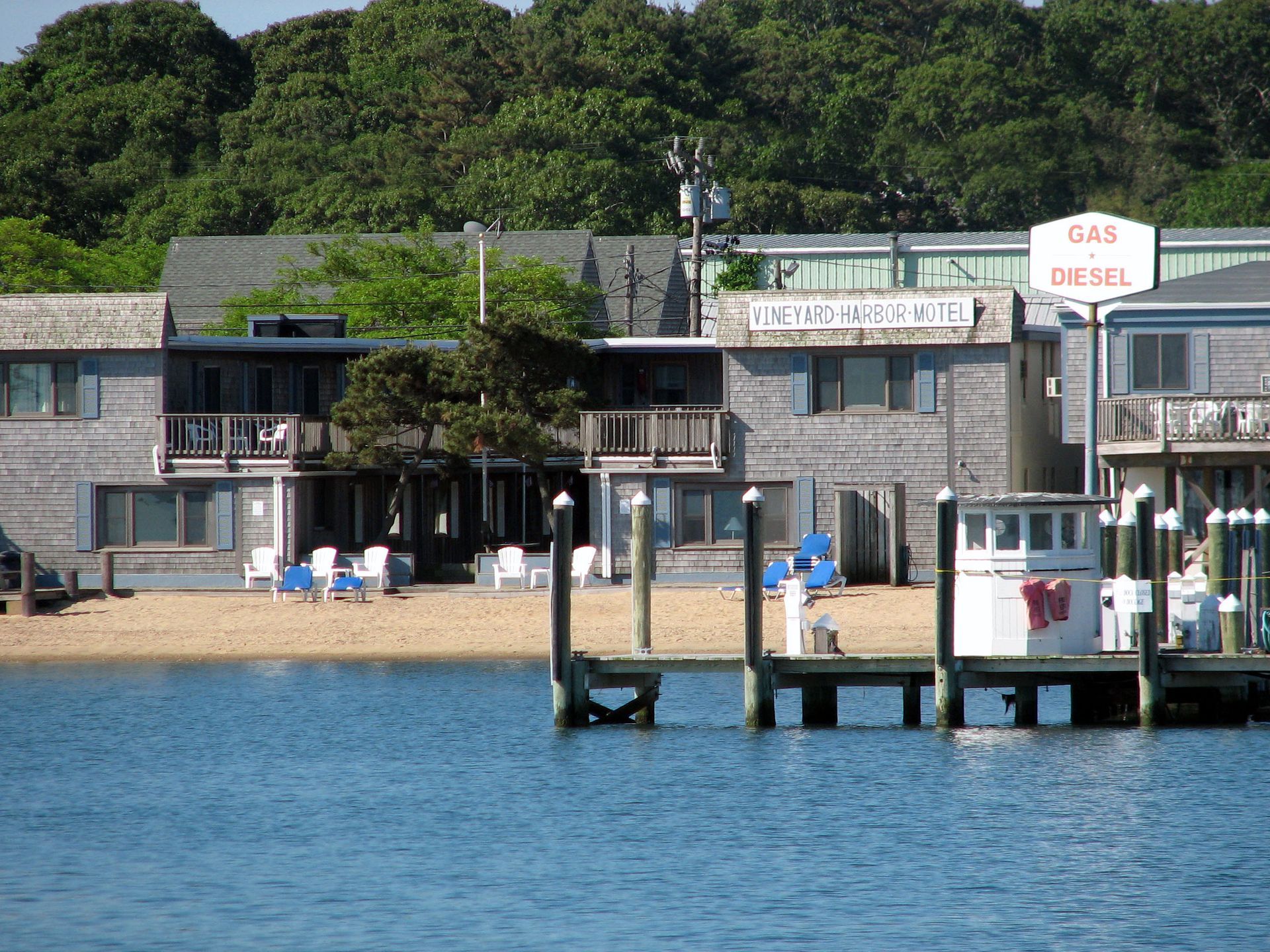 Beachfront buildings with a dock, small beach area, and gas/diesel sign.
