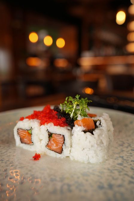 Sushi-Rollen mit rotem Rogen und Kräutern auf einem Teller in einem sanft beleuchteten Restaurant