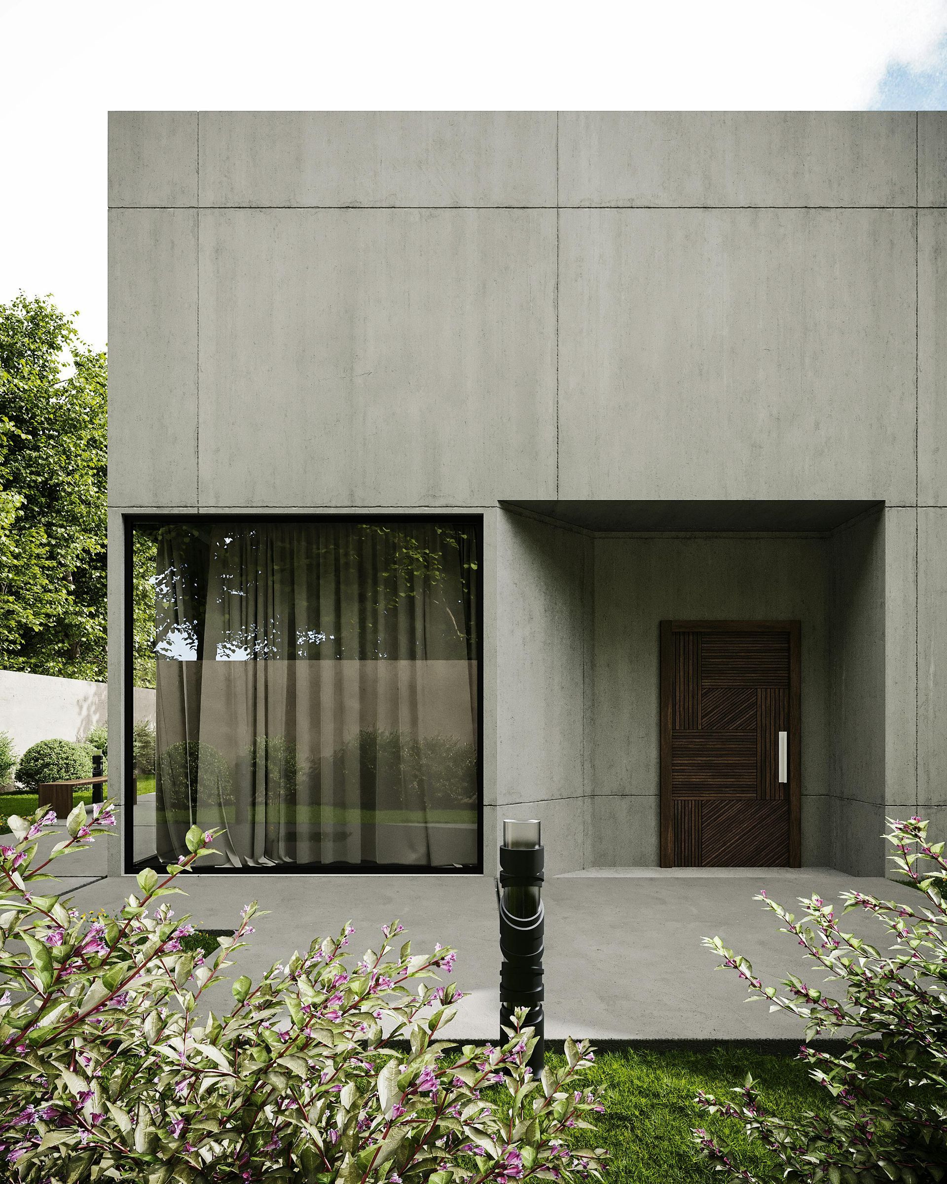 A minimalist grey concrete building exterior with a large window, a dark patterned door, and surrounding garden greenery.