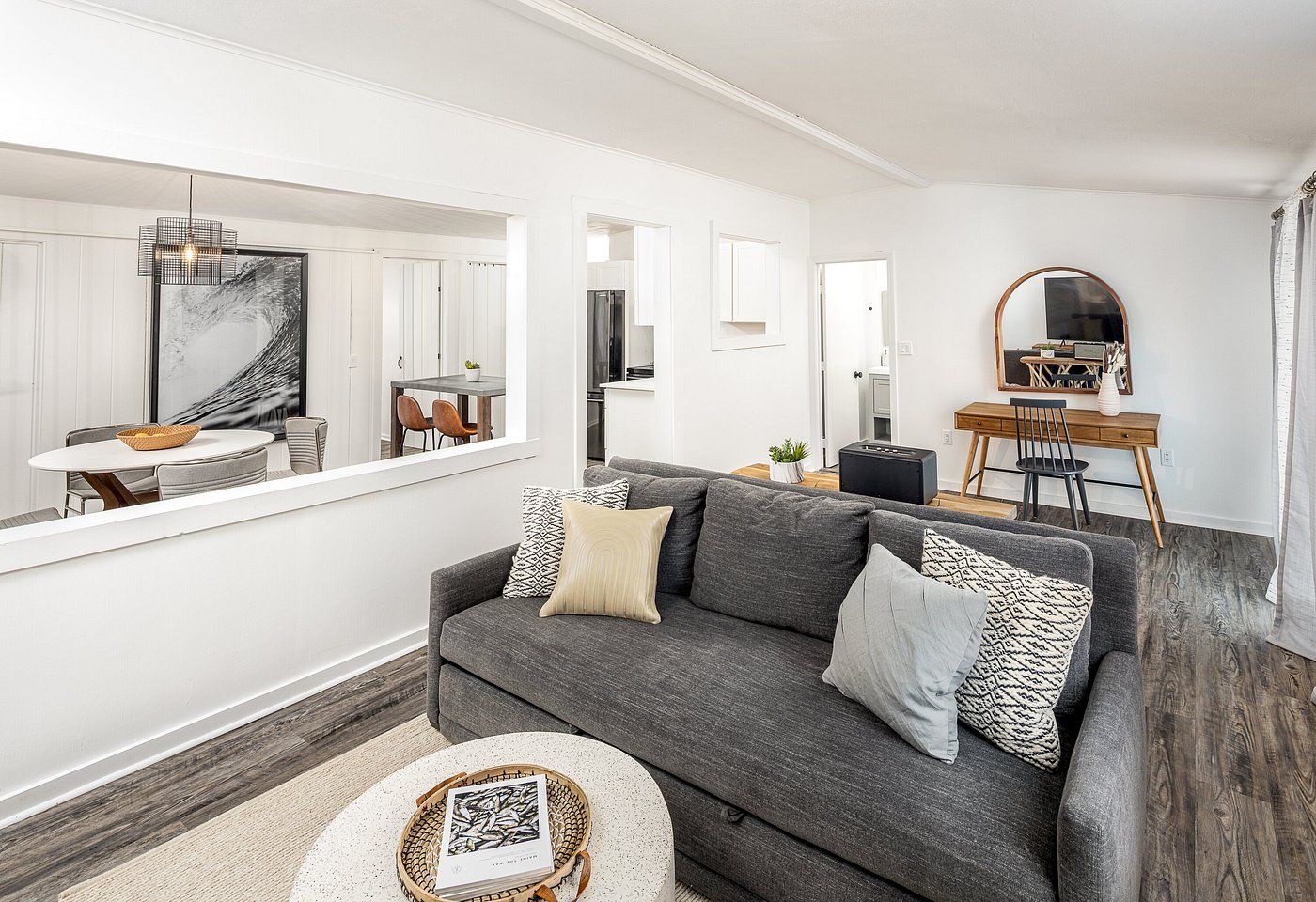 Living room with gray sofa, coffee table, and open wall to dining area.
